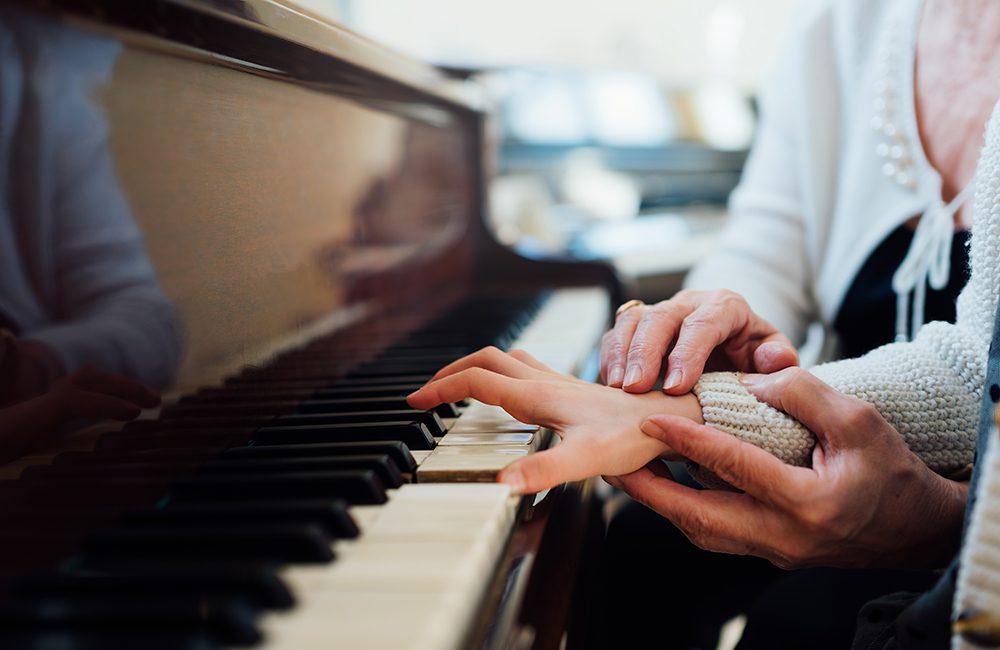 experienced hand of old music teacher helps child pupil